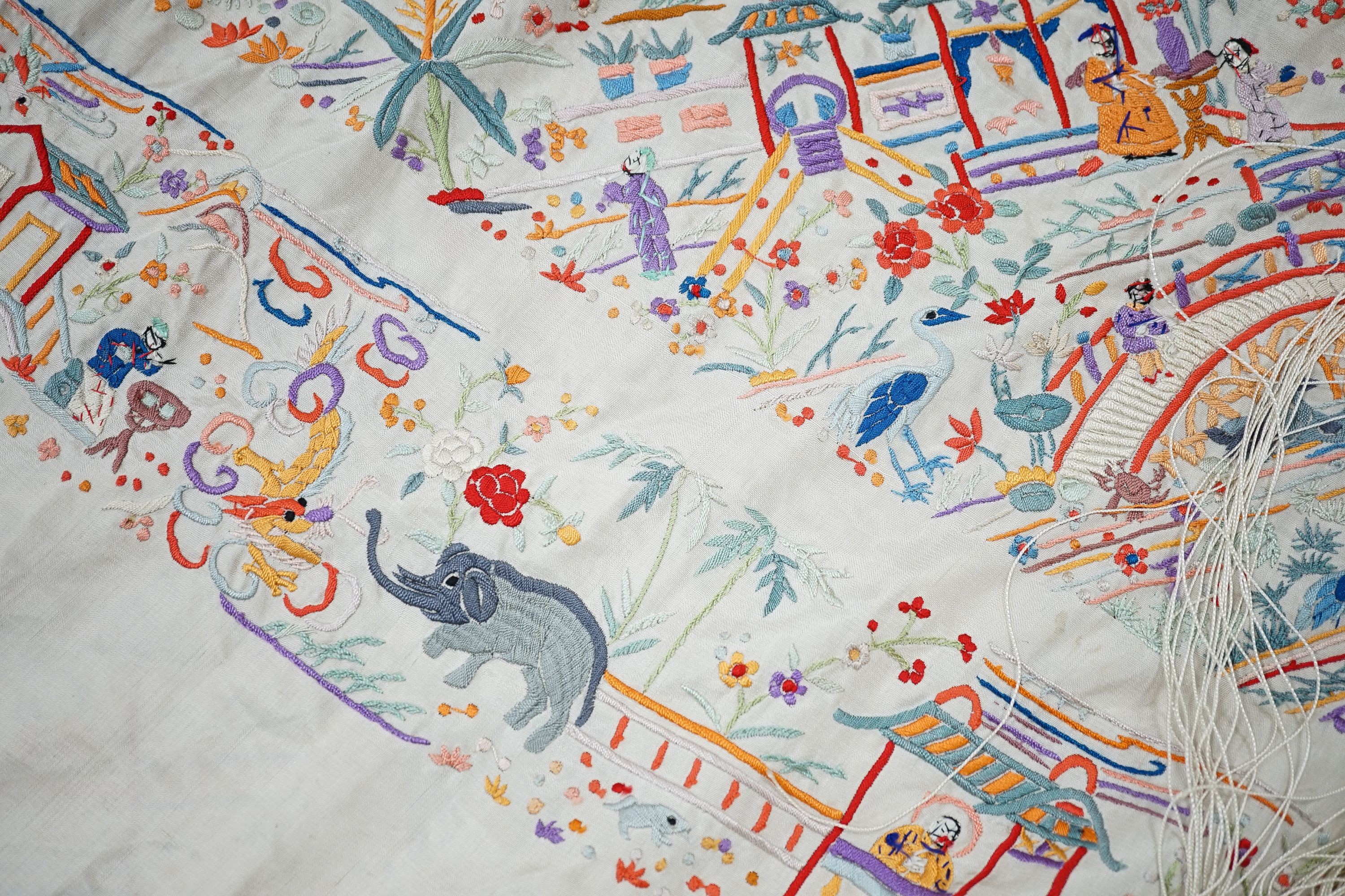 A Chinese cream silk shawl with fine multi coloured all over embroidery depicting figurative scenes and animals